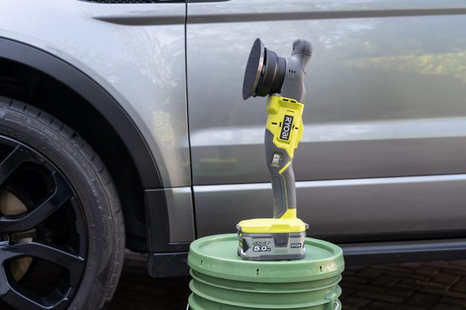 Ryobi One+ Dual Action Polisher stood next to clean car